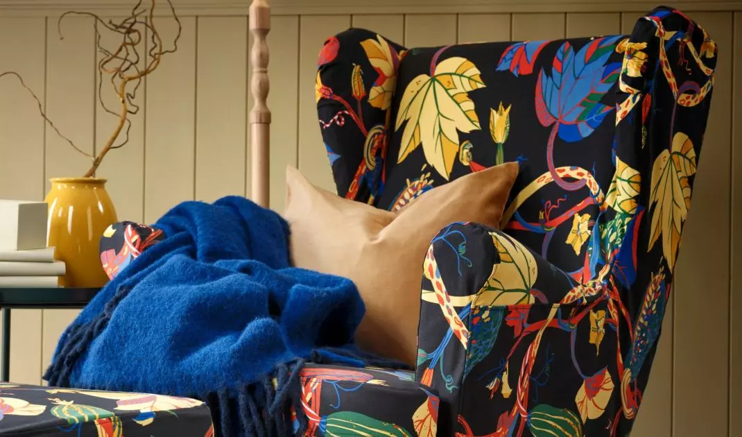 An earlobe armchair with a cover in a pattern of multicolored autumn leaves is the perfect choice for long evenings with a book