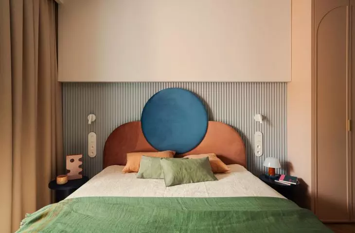 The headrest of the bed has an interesting form of two interpenetrating blocks in contrasting colors