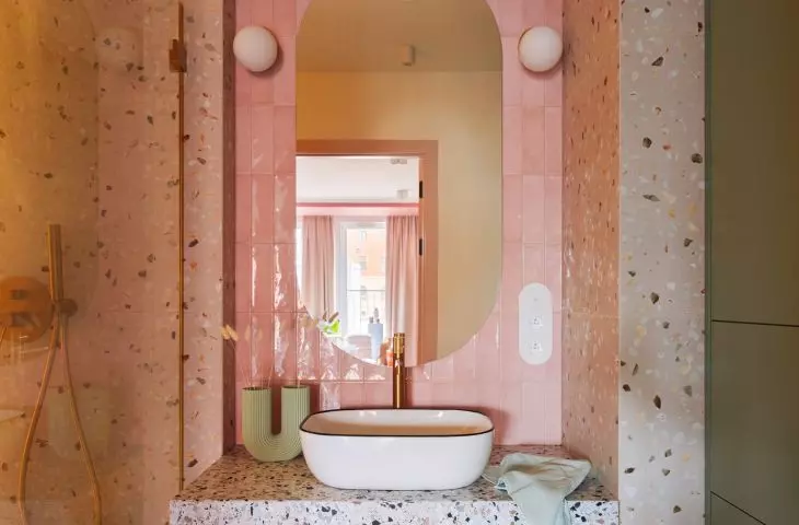 The wall above the sink was covered with glossy tiles in a pink shade