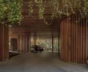 Rounded glass walls and wooden driveway finishes enhance the modern character of Carmichael's high-rise residential building 