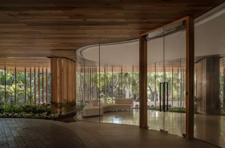 The lobby of the Carmichael residential high-rise impresses with its modern design, where rounded glass walls surround lush vegetation