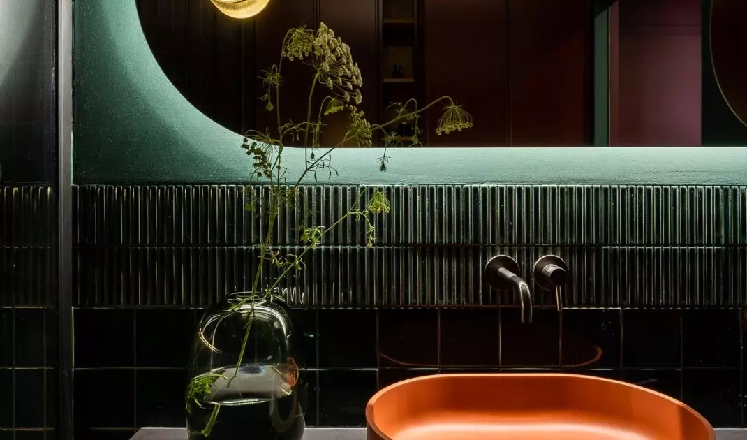 Orange washbasin breaks the dark color palette