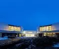 Modern building with large glass windows glowing against the dark blue evening sky