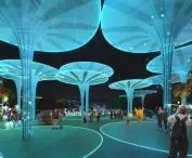 Futuristic outdoor space with glowing blue artificial trees at night and people interacting