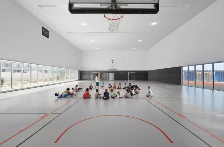 Modern indoor basketball court with children sitting in the middle