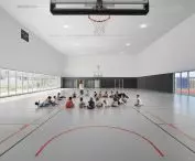 Modern indoor basketball court with children sitting in the middle