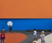 Children playing on school field with orange and blue wall