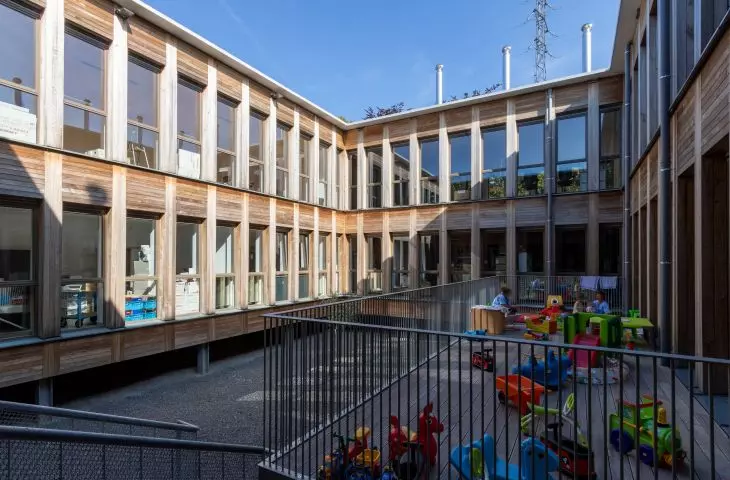 Two-story wooden building with a courtyard filled with toys for children