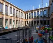 Two-story wooden building with a courtyard filled with toys for children