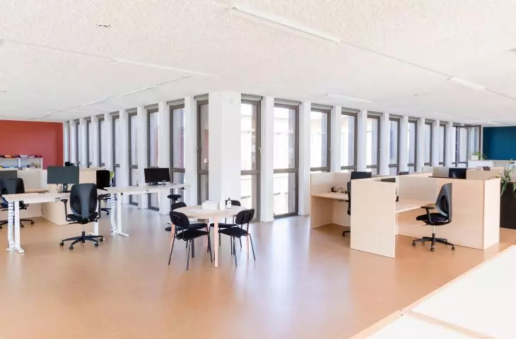 Modern office with workstations, large windows and black office chairs