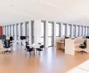 Modern office with workstations, large windows and black office chairs