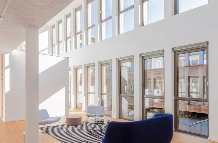 Spacious interior with large windows, wooden floors, modern furniture and striped carpet