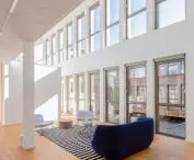 Spacious interior with large windows, wooden floors, modern furniture and striped carpet