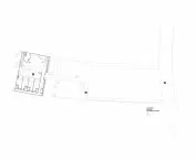 Architektoniczny plan terenu przedstawiający układ budynku z pomieszczeniami po lewej stronie i otwartą przestrzenią po prawej, wzdłuż drogi