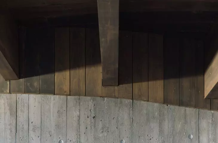 Zacienione drewniane deski nad teksturowanym betonem