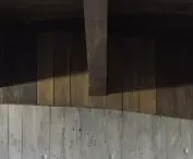 Zacienione drewniane deski nad teksturowanym betonem