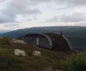 Budynek z zakrzywionym dachem na zboczu wzgórza, z widokiem na dolinę
