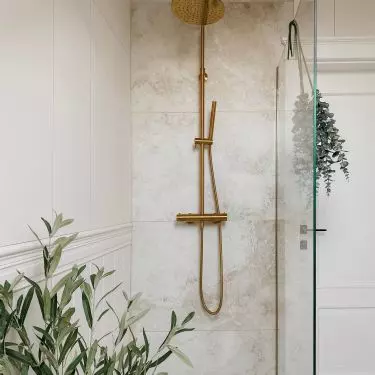 The walk-in shower consists of a sheet of tempered glass and a gold bracket