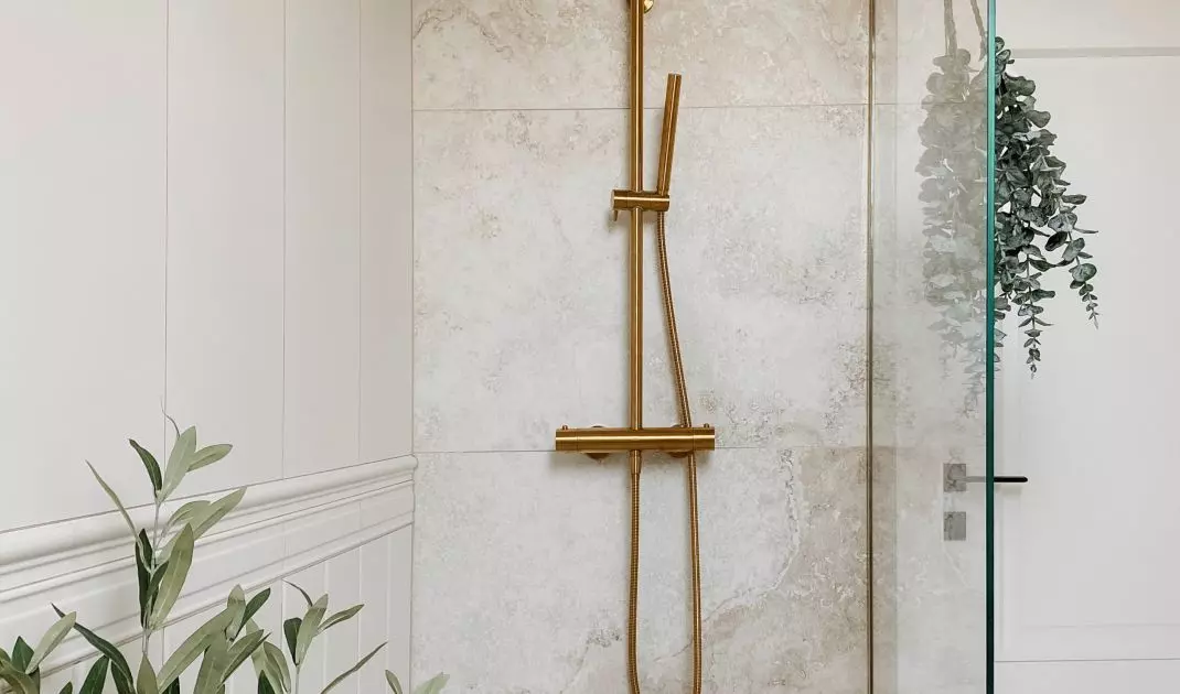 The walk-in shower consists of a sheet of tempered glass and a gold bracket