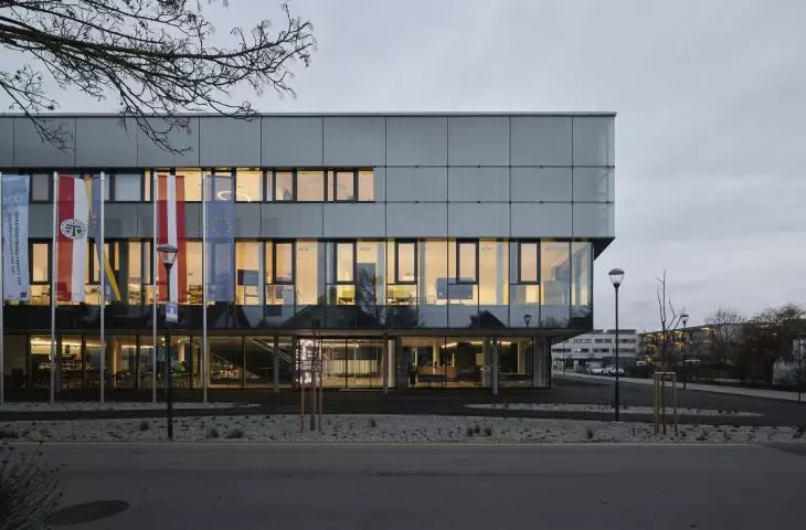 Szklane elewacje Domu Cyfryzacji w Tulln odbijają niebo i wyświetlają teksty, tworząc efekt treści unoszących się w chmurach