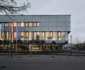 The glass facades of the Digitization House in Tulln reflect the sky and display texts, creating the effect of content floating in the clouds