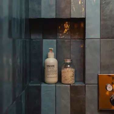 The walls of the shower are lined with blue tiles