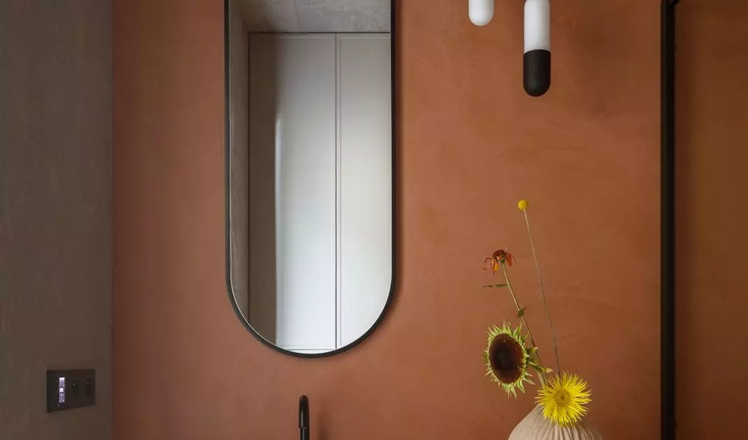 The walls of the bathroom are covered with sintered tiles in the shade of terracotta