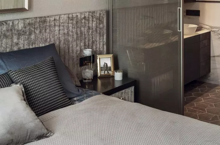 The bedroom is separated from the bathroom by a glass door