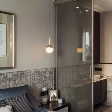 The bedroom is separated from the bathroom by a glass door