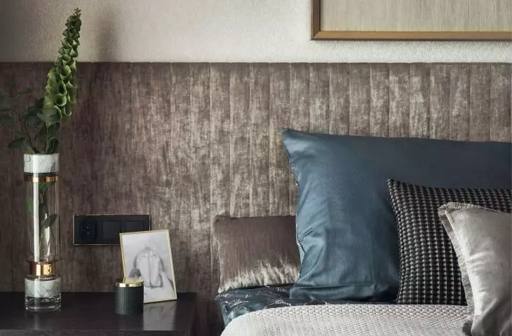 The wall behind the bed was covered with upholstered panels