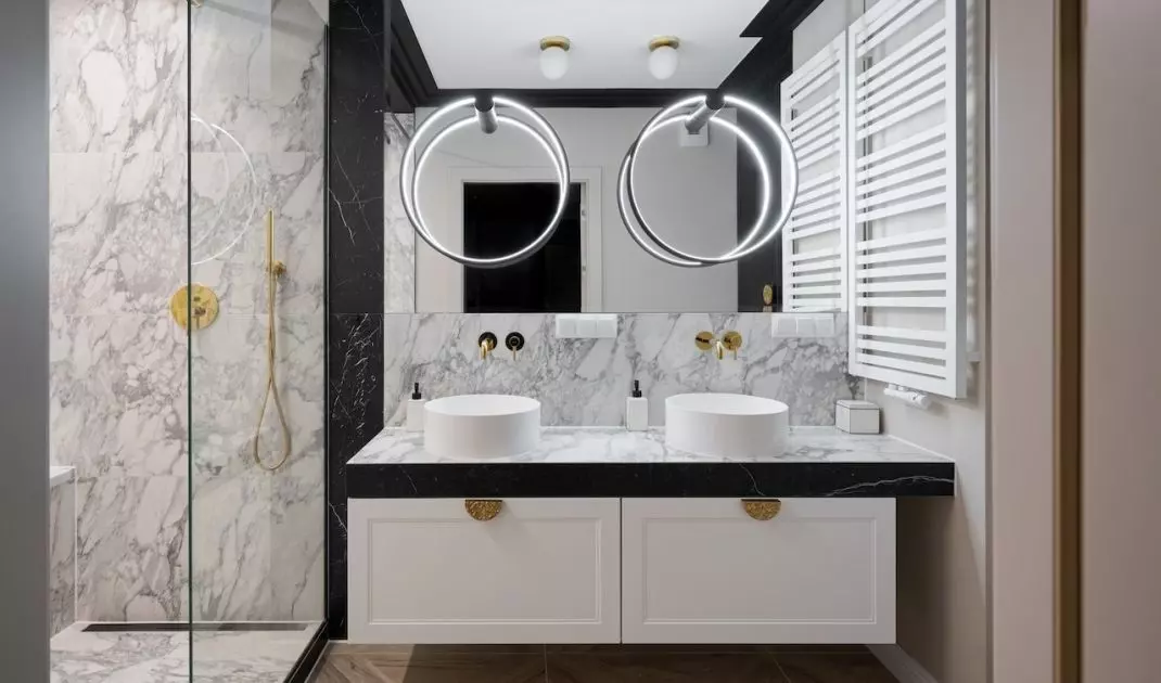 The circular lighting follows the shape of countertop washbasins