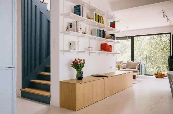 On one side of the wall is a bookcase, while on the other is a blue staircase