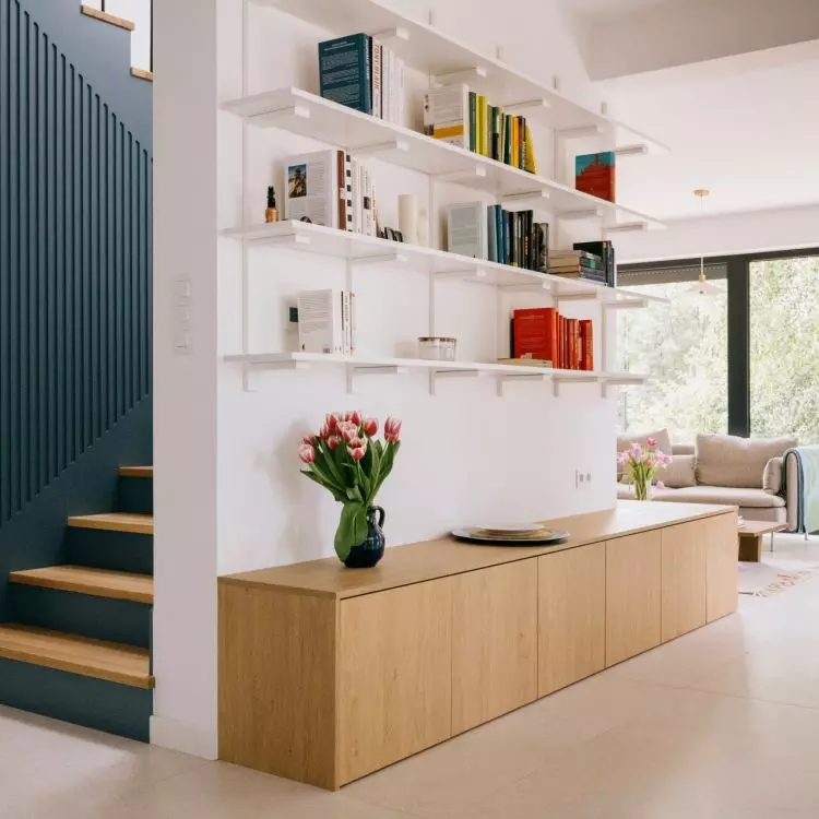 On one side of the wall is a bookcase, while on the other is a blue staircase