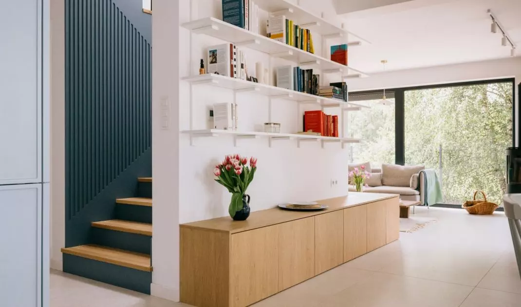 On one side of the wall is a bookcase, while on the other is a blue staircase
