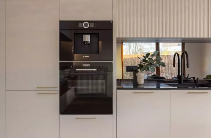 The cream-colored kitchen cabinets are complemented by gold handles