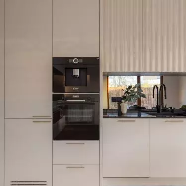 The cream-colored kitchen cabinets are complemented by gold handles