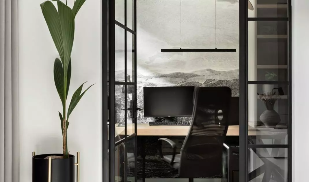 A wall in the study is decorated with wallpaper with a landscape motif