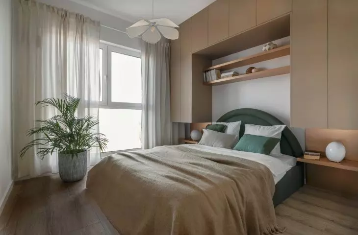 The bedroom has a bed with an upholstered headrest in green color