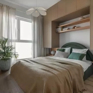 The bedroom has a bed with an upholstered headrest in green color