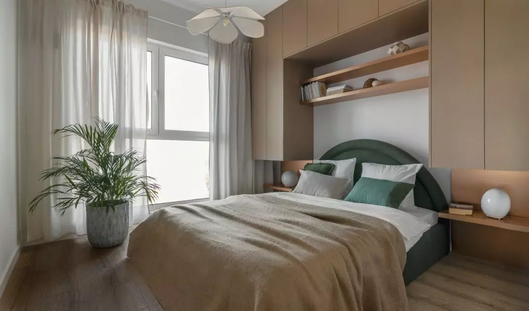 The bedroom has a bed with an upholstered headrest in green color