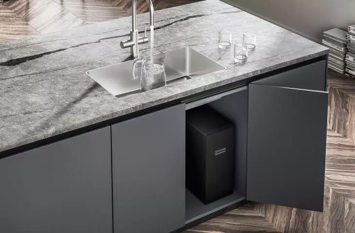 The device is mounted in the cabinet under the sink