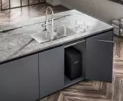 The device is mounted in the cabinet under the sink