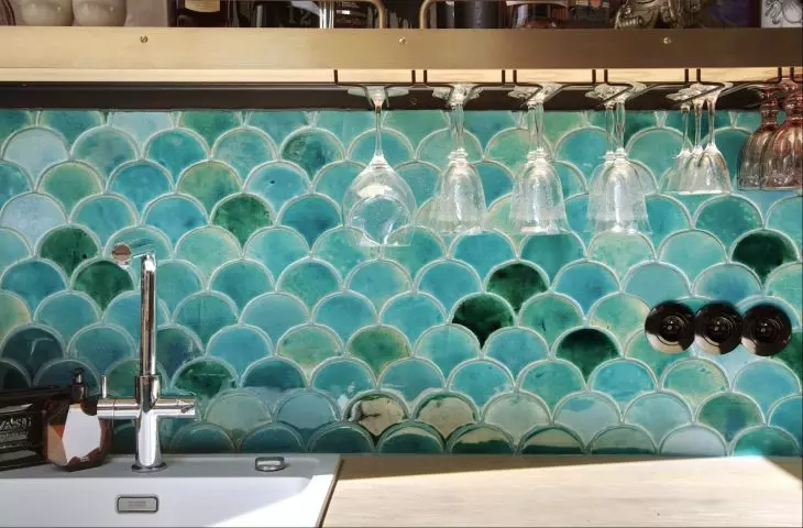 The wall above the countertop in the kitchen was finished with tiles with a fish scale motif