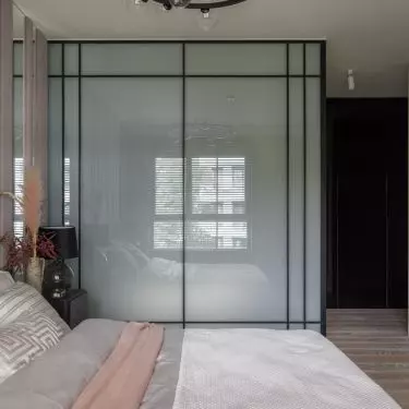 The bedroom is connected to the bathroom arranged in a glass cubicle