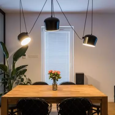 Above the dining room table hangs an interesting composition of black lamps