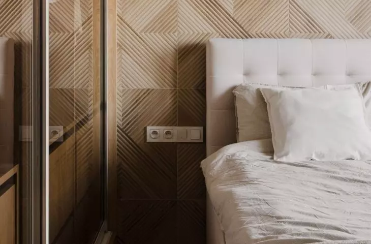 The wall behind the bed was covered with three-dimensional wood panels