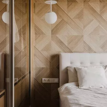 The wall behind the bed was covered with three-dimensional wood panels
