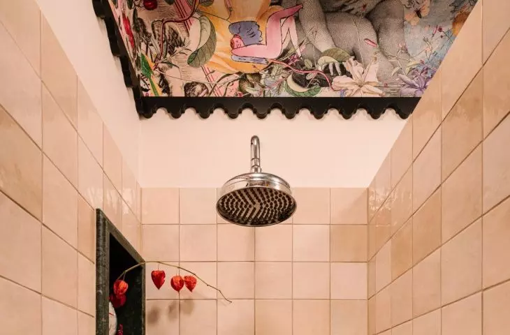 The bold bathroom design is balanced by beige tiles used in the shower area