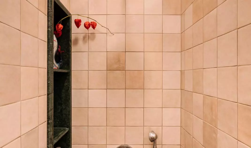 The bold bathroom design is balanced by beige tiles used in the shower area