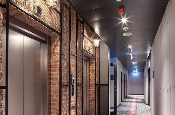 At the Moxy chain hotel (pictured left) in Warsaw's Praga district, the ceiling is decorated with dark panels that harmonize with the gray carpeting.